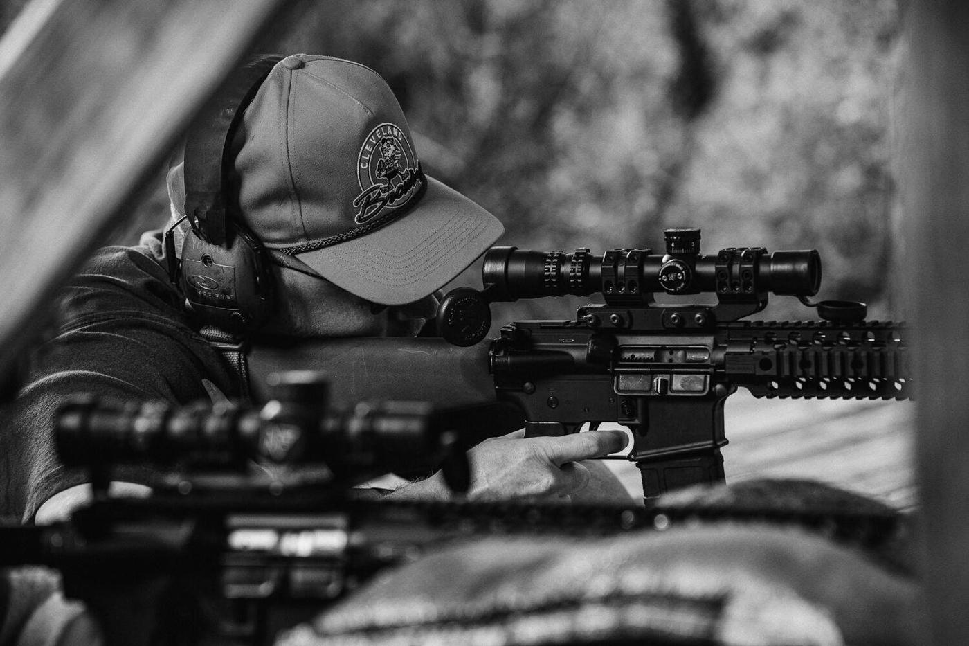 Shooter in an orange cap aiming a rifle at the range