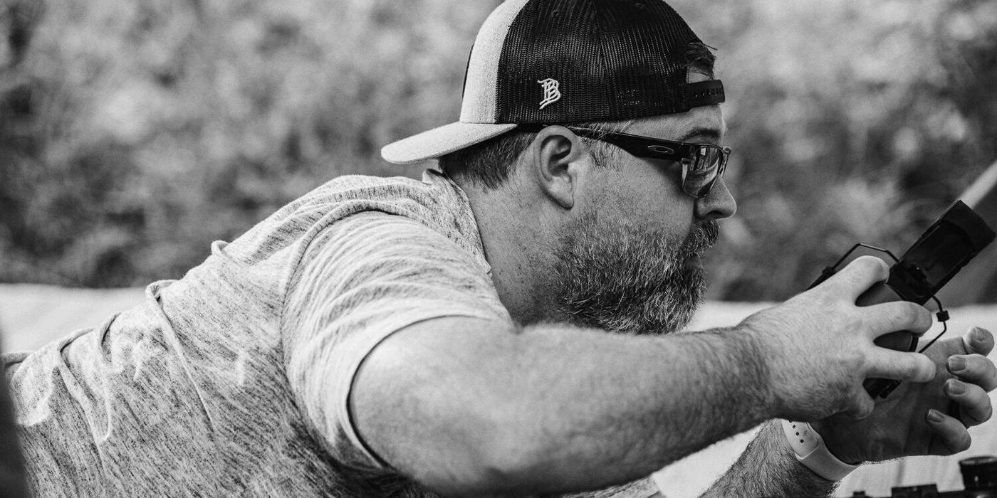 Shooter looking through a rifle scope at an outdoor range