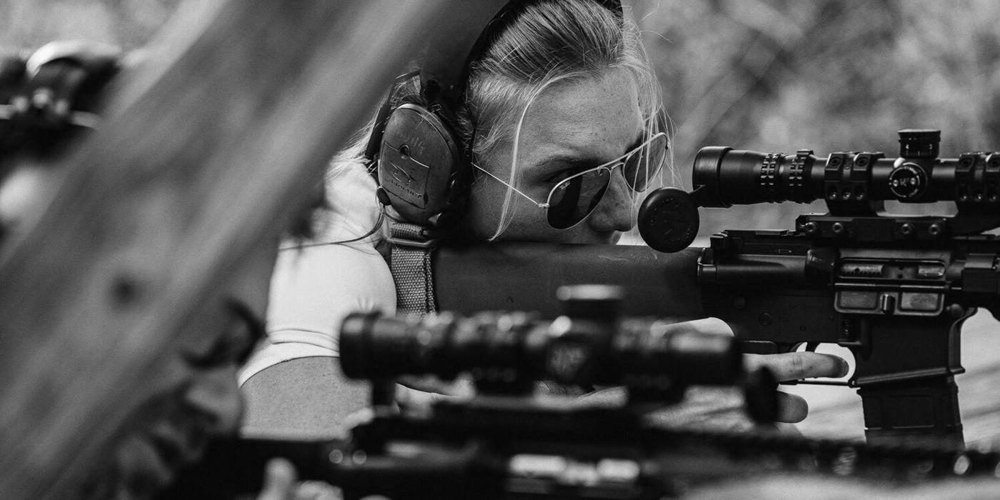 Shooter holding a rifle at the ready on an outdoor range