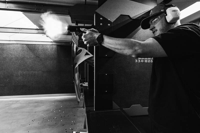 Ballistic team member firing a handgun in an indoor shooting bay